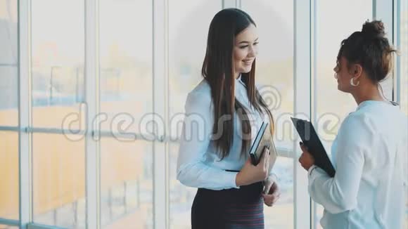 两个年轻漂亮的女孩在办公室里互相交谈视频的预览图