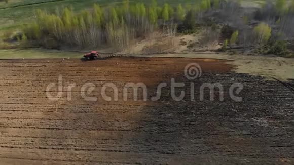 强大的红色拖拉机与犁工作犁处理黑暗土壤的背景下惊人的风景视频的预览图