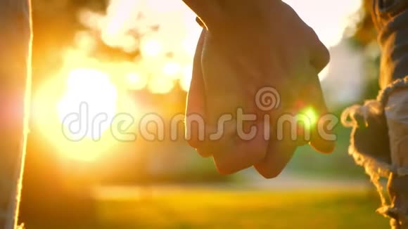 阳光背景下的镜头是双手相握可爱的夫妇正站在公园里视频的预览图