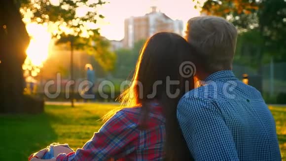 两个相爱的可爱的人紧紧地坐在令人惊叹的夏日公园里阳光照耀着到处都是模糊的景色可爱的视频的预览图