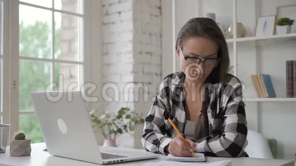 女设计师在她的投资电脑上检查蓝图在笔记本上写错误律师视频的预览图