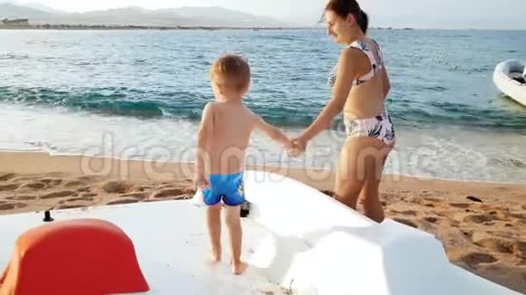 4k视频小男孩站在沙滩双体船上视频的预览图