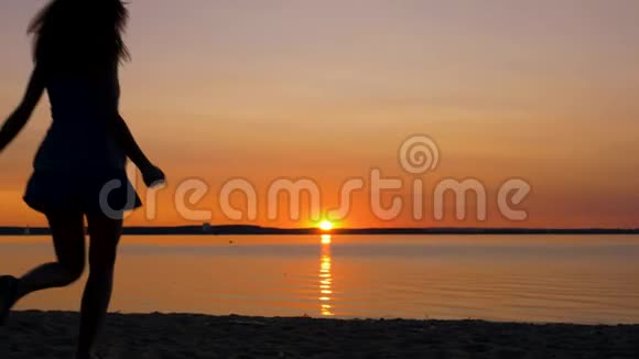 女人在沙滩上向日落奔跑举起双手转身视频的预览图