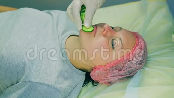 戴手套的化妆师的手在女人脸上贴上黄瓜片视频的预览图