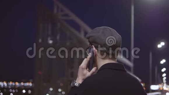 晚上站在河边的一个城市里一个年轻的帅哥在打电话视频的预览图