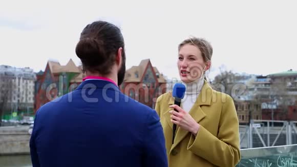 年轻有魅力的女记者正在城里采访一位年轻的商人从事媒体电视工作的年轻妇女视频的预览图