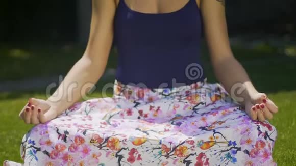 女瑜伽师在户外坐在莲花位置盘面对特写公园视频的预览图