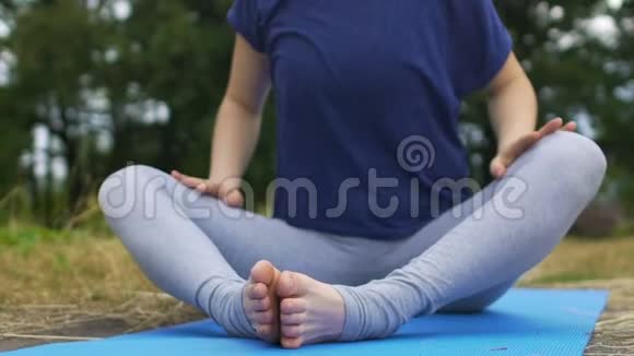 女人在蝴蝶的位置伸展双腿向前弯曲瑜伽在公园阿萨纳视频的预览图