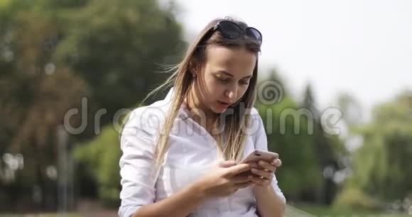 开朗的女模特在户外的电话上写一条信息视频的预览图