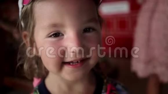 一个三岁的女孩戴着帽子微笑的肖像有些东西显示出缓慢的运动视频的预览图