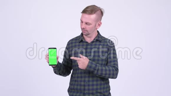 一幅快乐的金发时髦男人展示电话和竖起大拇指的肖像视频的预览图