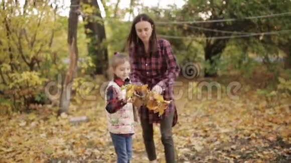 可爱的小女孩和她的母亲一起打扫秋叶视频的预览图