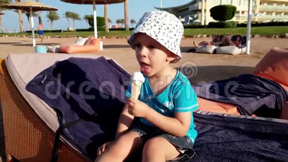 4k段可爱的小男孩坐在日光浴床上吃冰淇淋视频的预览图