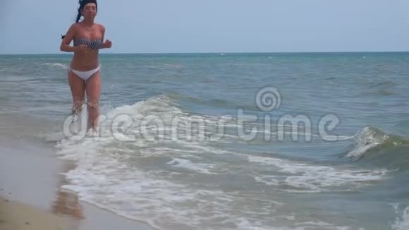 女孩沿着海岸跑慢动作视频的预览图