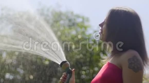 微笑快乐的女士转向相机浇水在阳光明媚的天气慢动作视频的预览图