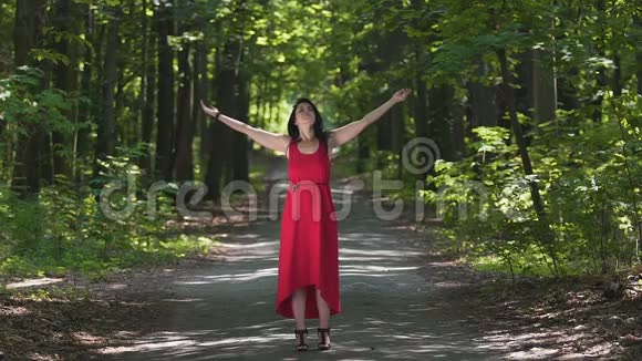 红衣女子享受大自然感受与神圣森林精神的统一祝福视频的预览图