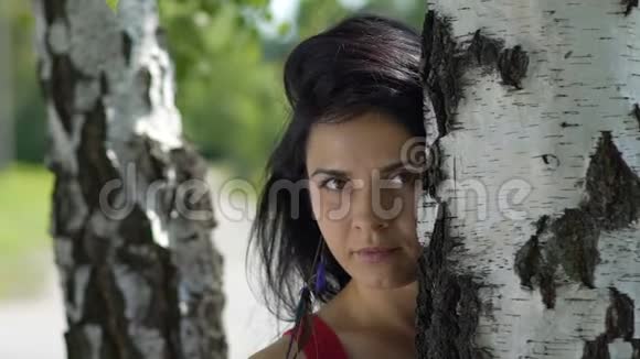 严肃的女人看公园慢动作深色头发的美女靠近树悲伤的女性视频的预览图