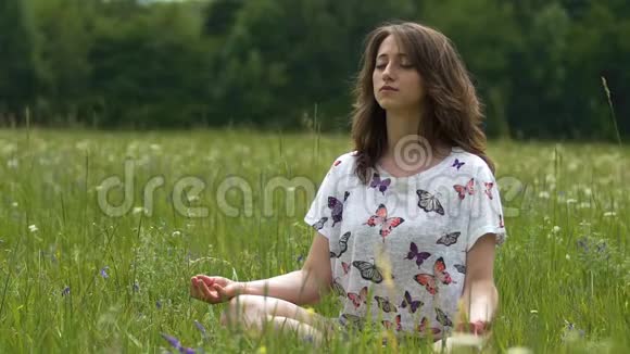 夏季女性在户外绿草上冥想坐着莲花集中视频的预览图
