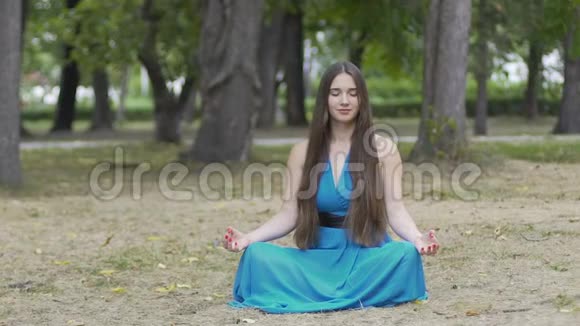 穿着蓝色裙子的漂亮女人在户外冥想在广告文字的地方多莉拍摄视频的预览图