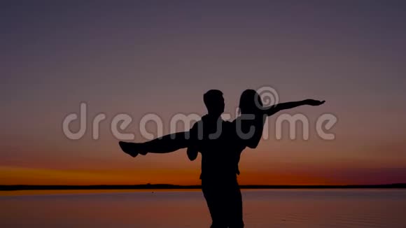 一个男人抱着一个女人在海边日落时围着她转的剪影视频的预览图