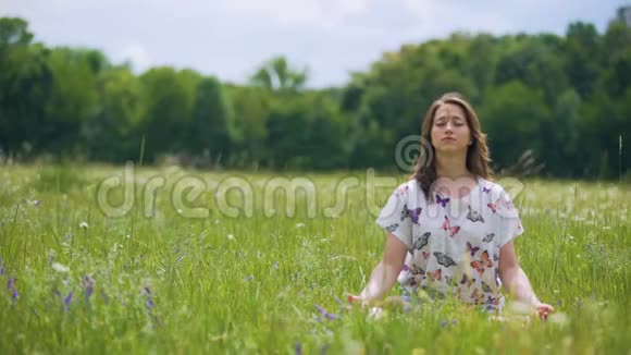 女人坐在莲花的姿势在户外冥想风动头发合一的自然视频的预览图