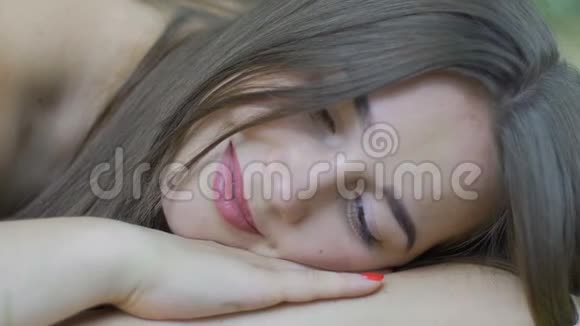 微笑的女人躺在户外睁着眼睛看着镜头美丽的女孩在公园里视频的预览图