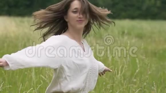 笑着跳舞的女人伸出双手旋转快乐在户外视频的预览图