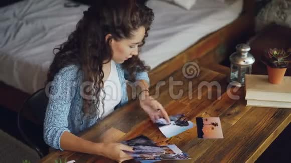女摄影师正在看坐在桌子旁的照片把照片放在木桌上阁楼式公寓视频的预览图