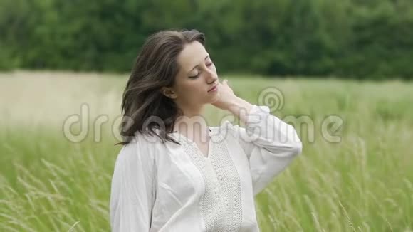 女人闭着眼睛站在田野里感受风和自然的合一视频的预览图