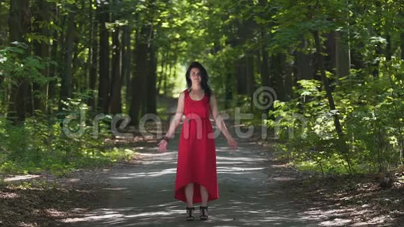 美丽的红衣女郎在森林里举手大自然的力量团结的喜悦视频的预览图