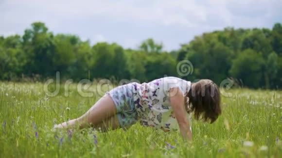 年轻女性在绿草中练习瑜伽户外瑜伽更接近自然体式视频的预览图