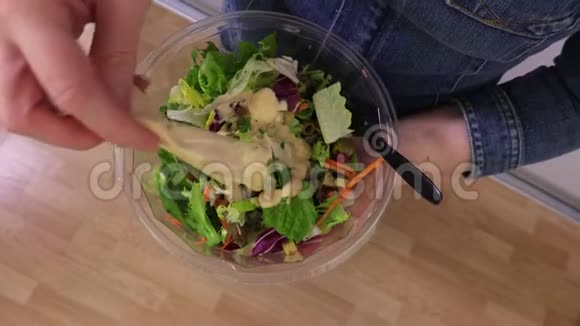 女人在蔬菜沙拉中添加酱汁俯视视频的预览图