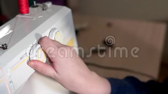 裁缝在缝纫机上选择模式她用手转动开关照相机滑到视频的预览图
