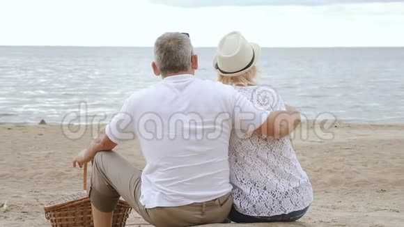 一对老夫妇坐在海滩上望着大海视频的预览图