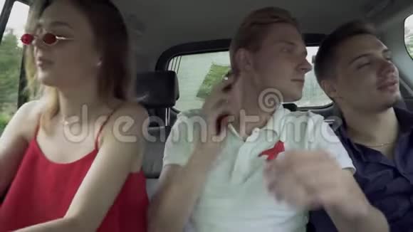 朋友的陪伴在车上旅行两个年轻人和一个漂亮的女孩在汽车沙龙车里的青少年视频的预览图