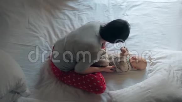 穿睡衣的女人和可爱的孩子在床上爱妈妈玩小男孩视频的预览图