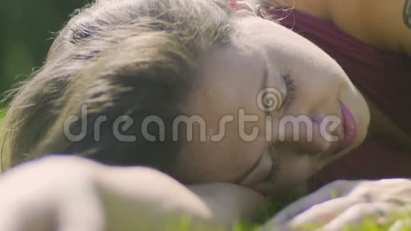 美丽的女性纹身躺在草地上的特写平底锅风的夏天户外视频的预览图