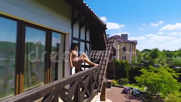 漂亮的女人坐在阳台的边缘度过夏天放松无忧无虑视频的预览图