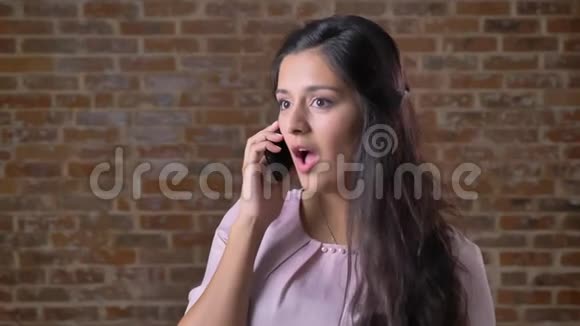 一位美丽的白种人女人正在平静地用电话交谈抚摸她的头发咬着她的嘴唇微笑着视频的预览图