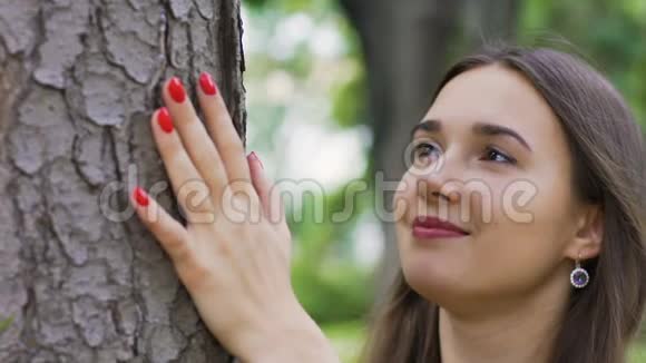 女人拥抱一棵树看起来充满爱与自然团结生活平静慢动作视频的预览图