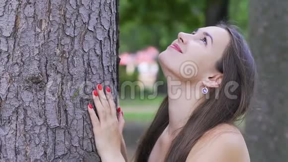 美丽的女人微笑着仰望树幸福的女人在大树下享受大自然视频的预览图