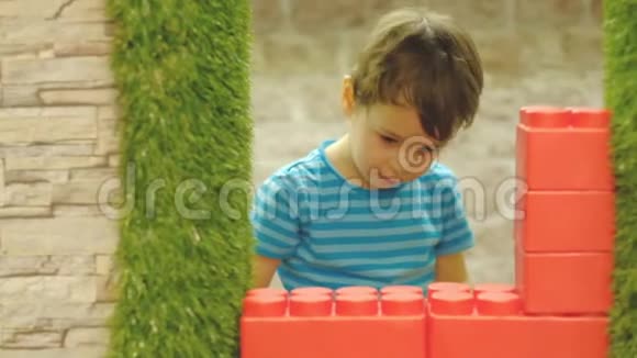 男孩三岁独自在孩子们房间里玩耍站着一堵大塑料块的墙视频的预览图