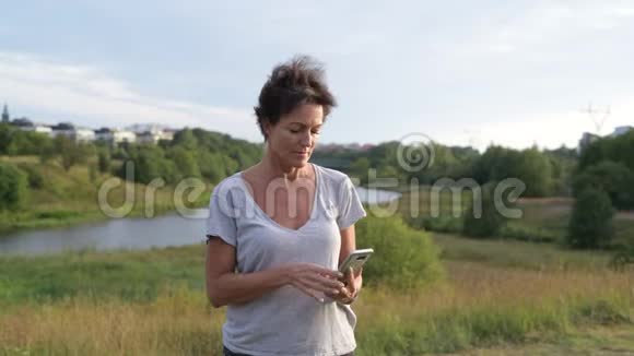 快乐成熟美丽的女人微笑着放松的自然景观自拍视频的预览图
