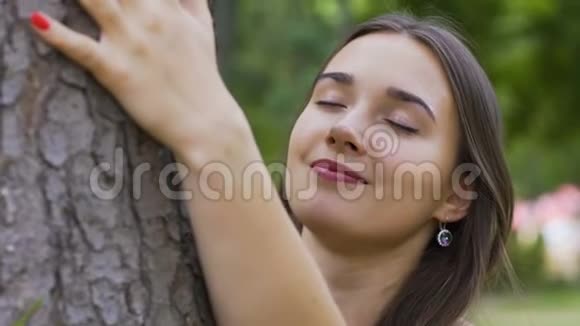 年轻的美女爱抚树木热爱大自然感受和平与统一视频的预览图