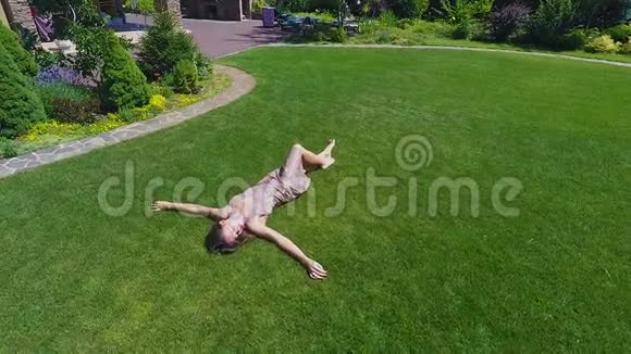 美丽的梦中女郎在草地上度过无忧无虑的夏天放松地躺着视频的预览图