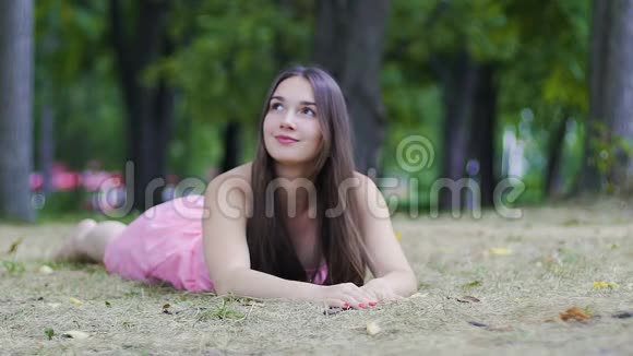 美丽的女性躺在草地上感到快乐和幸福调情微笑户外公园视频的预览图