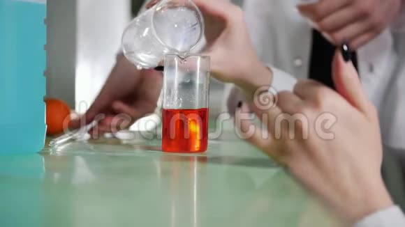 一位妇女在医学实验室里把橙色液体和白色混合在一起视频的预览图