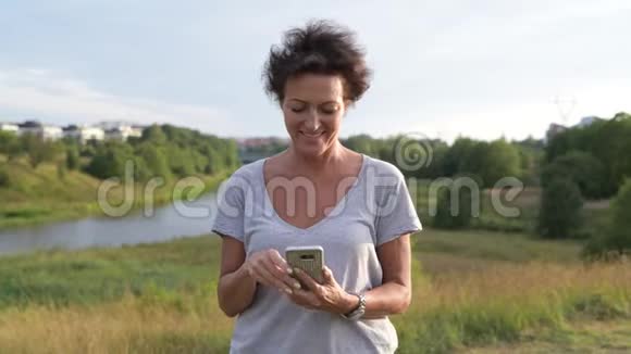 快乐成熟美丽的女人一边用电话一边思考一边放松自然观视频的预览图