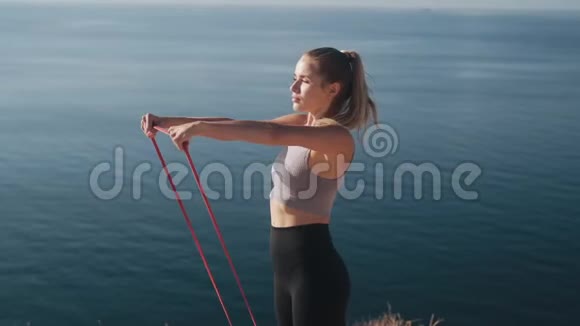 女人在户外用橡皮筋锻炼身体锻炼身体慢动作视频的预览图