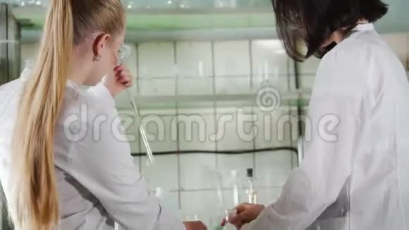化学实验室两名年轻的实验室技术人员在烧瓶中进行液体实验视频的预览图
